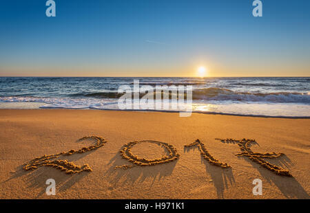 Number 2017 written on seashore sand at sunrise. Concept of upcoming new year and passing of time. Stock Photo