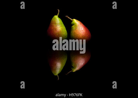 Two whole red and green pears isolated on black reflective background Stock Photo