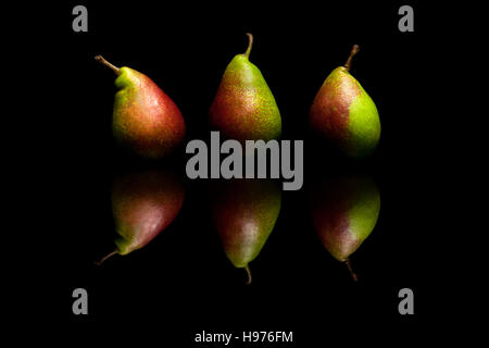 Three whole red and green pears isolated on black reflective background Stock Photo