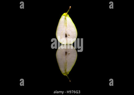 Cut in half one pear isolated on black reflective background Stock Photo