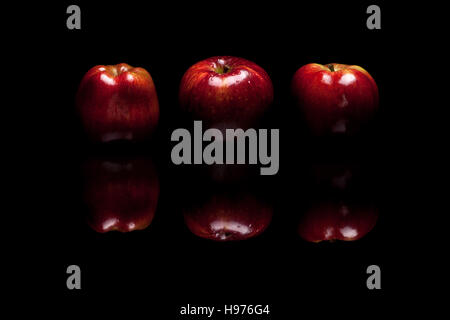 Three red apples isolated on black reflective background Stock Photo