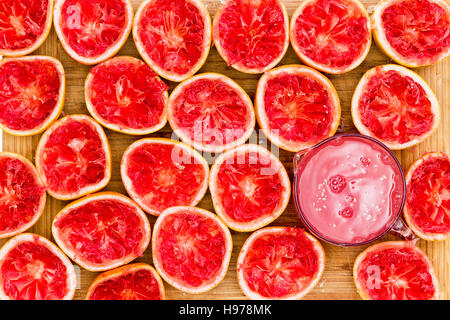 Delicious ruby red grapefruit halves by glass against a wooden background as seen from an overhead view Stock Photo