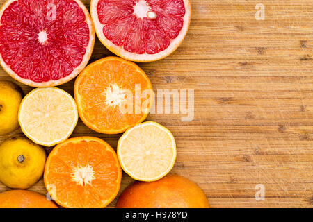 High Angle Still Life View of Sliced Ripe Ruby Red Grapefruit, Oranges and Lemons Arranged on Rustic Wooden Cutting Board with Copy Space Stock Photo