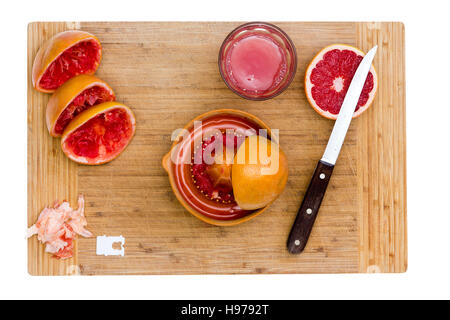 Fresh Grapefruits being Juiced, Ruby Red Grapefruit on Wooden Kitchen Board isolated on white Stock Photo