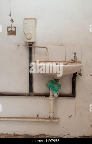 Hand wash basin and electric water heater in an abandoned industrial building Stock Photo