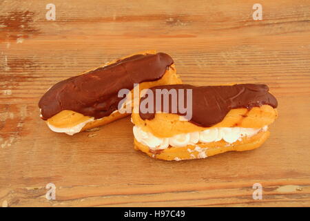Two chocolate eclairs isolated on a wooden surface image in landscape format with copy space Stock Photo