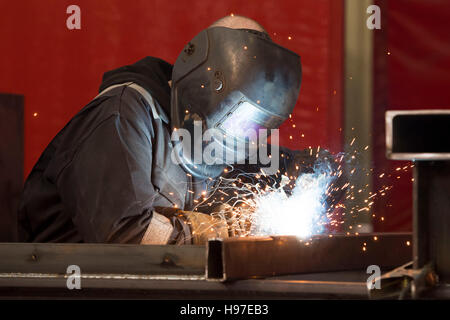 A male welder welding steel metal in a workshop. Stock Photo