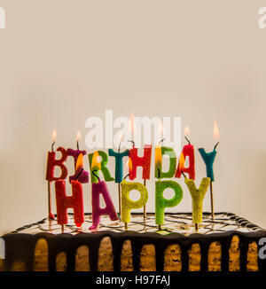 Happy birthday candles burning on chocolate cake isolated on white or gray background. Stock Photo