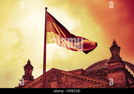 German flag flies above the Reichstag Building on an ominous day in Berlin Stock Photo