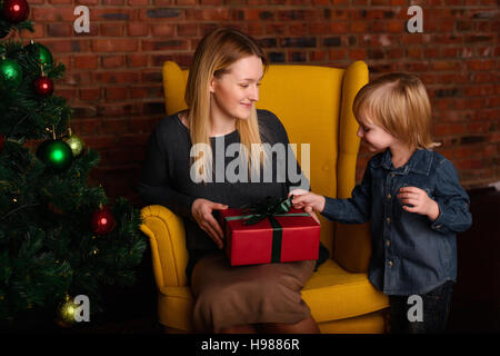 Mother gives Christmas gift to his little son for a New Year. Mom and son  opening Christmas presents Stock Photo - Alamy