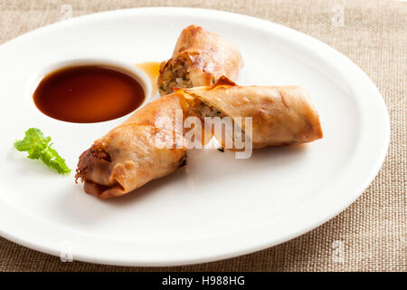 Fried spring rolls with vegetables and shrimps, served on white plate with vinegar Stock Photo
