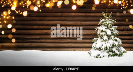 Christmas frame with wooden background, snow covered fir tree and glowing defocused lights Stock Photo