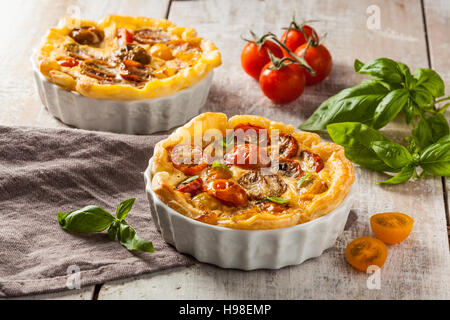 Quiche with cherry tomatoes on a rustic wooden table. Stock Photo
