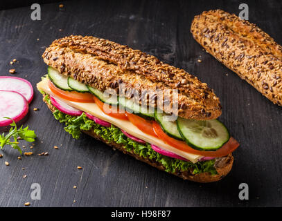 Sandwich with cheese, tomato, cucumber, radish and lettuce. Dark and moody. Stock Photo