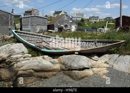 An old wooden boat by huts and houses in the fishing village of Peggy's Cove in Nova Scotia, Canada. Stock Photo