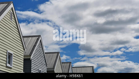Heading North in the nordic landscape: a row of houses built in typical wooden architecture, blue sky and clouds