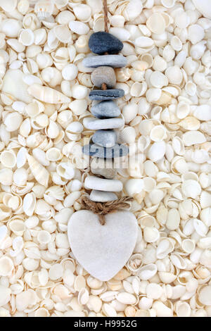 Heart and pebble mobile on white seashell abstract background. Stock Photo