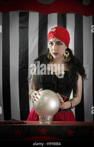 Beautiful young female with  crystal ball ready to read the future in circus setting Stock Photo