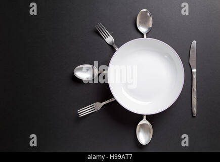 White plate with cutlery over black background.Useful as background for food, restaurant menu or other Stock Photo