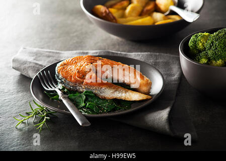 Grilled salmon steak with vegetables on dark background. Stock Photo