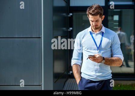 Businessman with smartphone text messaging outdoors Stock Photo