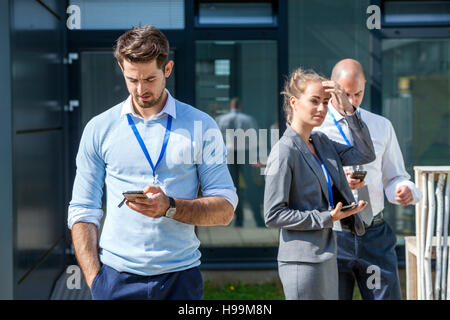 Business people using smartphones outdoors Stock Photo