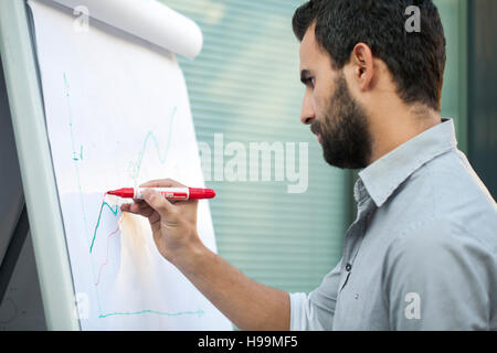 Businessman writing with marker on flipchart Stock Photo