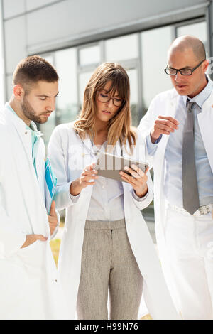 Group of doctors using digital tablet outdoors Stock Photo