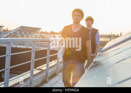 Construction workers walking on roof of solar power station Stock Photo