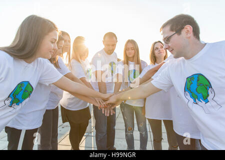 Group of teenage environmentalists joining hands in circle Stock Photo