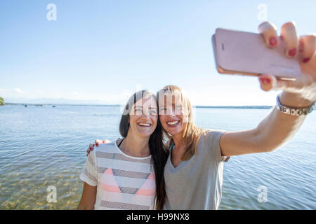 Two young women taking selfie by lake Stock Photo