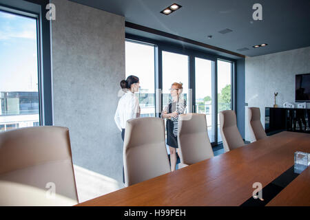 Two businesswomen talking in board room Stock Photo