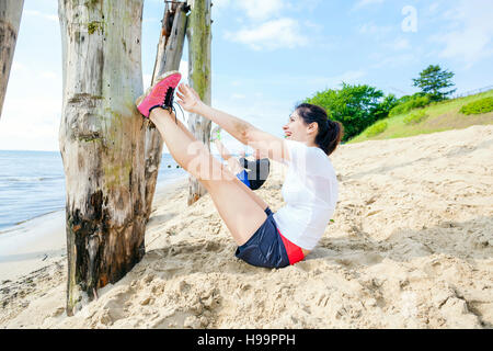 Young women on beach doing sit-ups Stock Photo