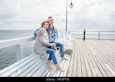 Couple in love sitting on jetty Stock Photo