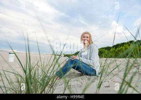 Woman with blond hair relaxing on sandy beach Stock Photo