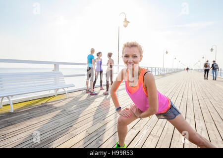 Woman on jetty doing stretching exercise Stock Photo