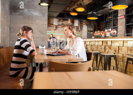 Two girlfriends in coffee shop having a conversation Stock Photo