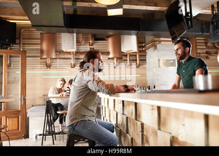 Man in coffee shop talking to bartender Stock Photo