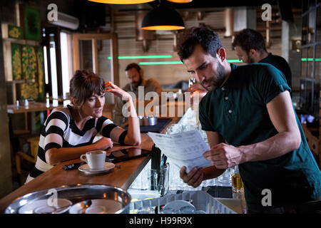 Woman at bar counter in coffee shop talking to bartender Stock Photo