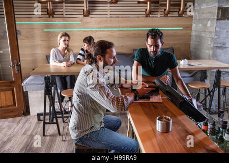 Male guest and bartender talking at bar counter in coffee shop Stock Photo