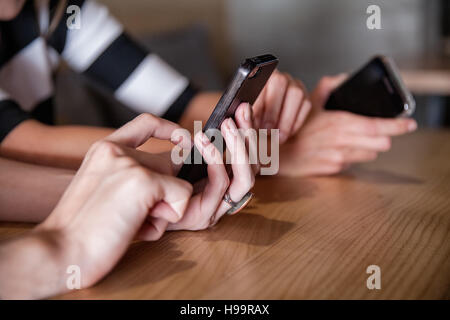 Two women in coffee shop using their smartphones Stock Photo