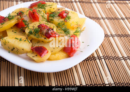 Closeup view on slices of potato stew with vegetables, red bell pepper and green fennel on tablecloth background Stock Photo