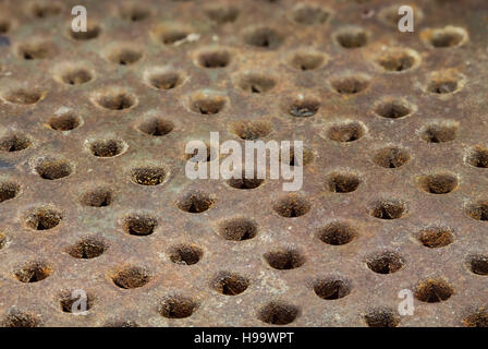 Rusty metal surface with round holes arranged in a row Stock Photo