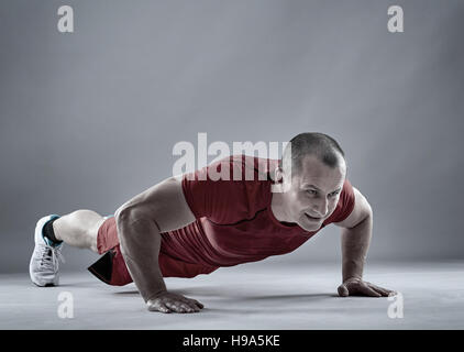 Fitness man doing pushups on gray background Stock Photo