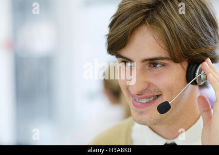 Smiling young call center executive at startup office Stock Photo