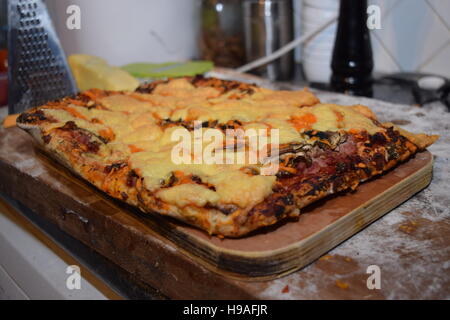 Homemade pepperoni pizza on  a wooden board photographed on dark wood with natural light Stock Photo