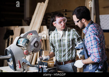 Two men builder with circular saw having a conversation Stock Photo