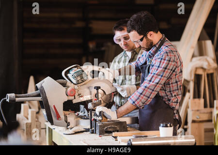 Framing contractor using a circular cut off saw to trim wood studs length. Stock Photo