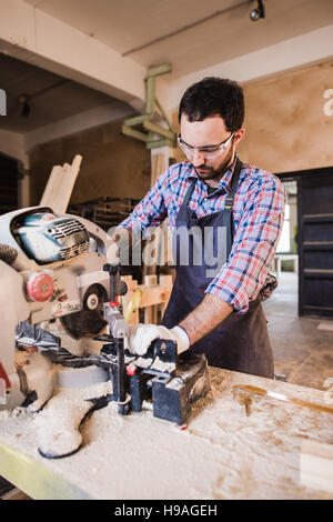 Young craftsman in uniform working at carpentry Stock Photo