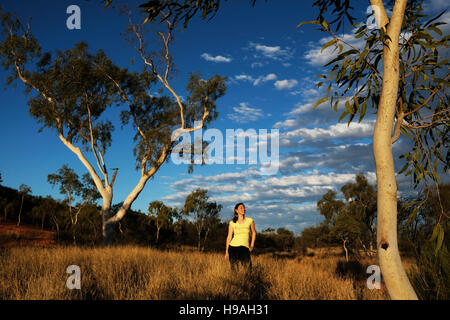 A woman is surrounded by gum trees in Alice Springs, the MacDonnell Ranges, Northern Territory, Central Australia Stock Photo